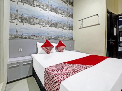 1 dormitorio con 1 cama blanca grande con almohadas rojas en Super OYO 91202 Family Guest House Syariah, en Tulungagung