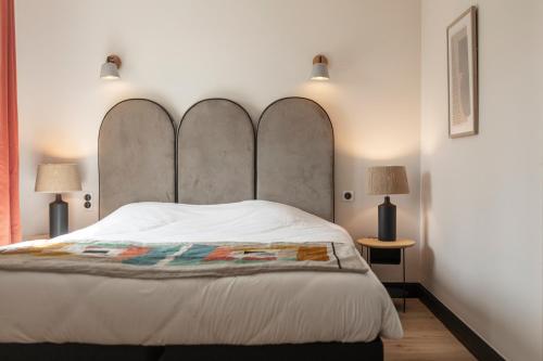 a bedroom with a large white bed with two lamps at Hôtel l'Arena in Fréjus