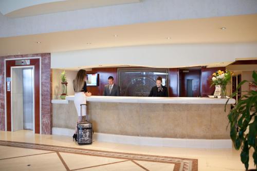 a woman standing at a bar in a hotel with her luggage at Mediterranean Hotel in Rhodes Town