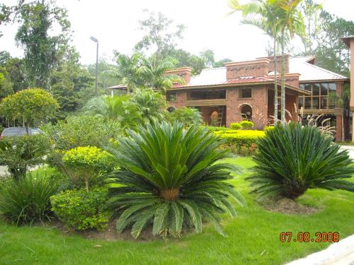 a garden with palm trees and a brick house at Hotel Gran Jimenoa in Jarabacoa