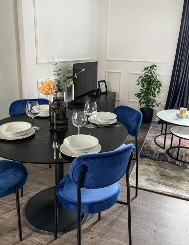 a dining room with a black table and blue chairs at Kamurke - Apartamentai in Šiauliai