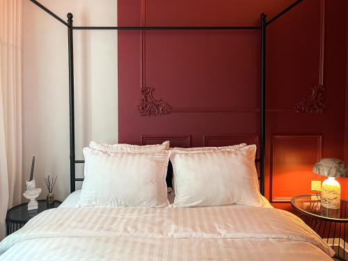 a bed with a red headboard and white pillows at Kamurke - Apartamentai in Šiauliai