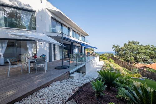 une maison avec une terrasse dotée d'une table et d'un parasol dans l'établissement Architect-Designed House Heated Pool and Sea View, à Mandelieu-la-Napoule