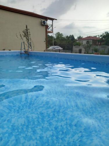 a swimming pool with blue water in a house at Апарт-отель "У речки" in Kuchkisabano