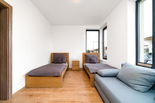 2 Betten und ein Sofa in einem Zimmer mit Fenstern in der Unterkunft Apartmán 1006 Čeladná in Čeladná