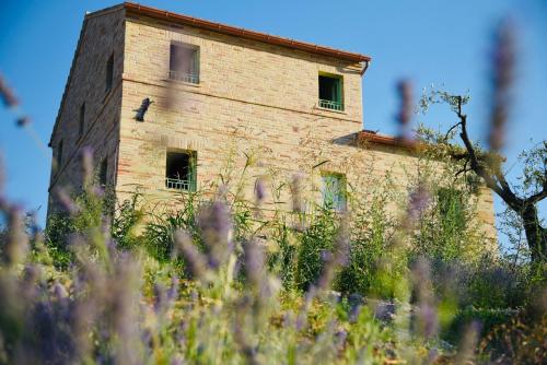 an old brick building in a field of grass at Il casale dei nonni in Grottazzolina
