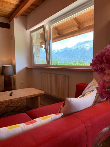 a living room with a red couch and a window at AGRITURISMO MODOLO Belluno Dolomiti in Belluno