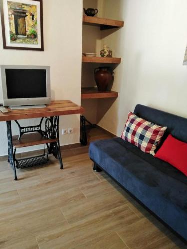 a living room with a couch and a desk with a tv at Casa Janeiro Alentejo in Portalegre