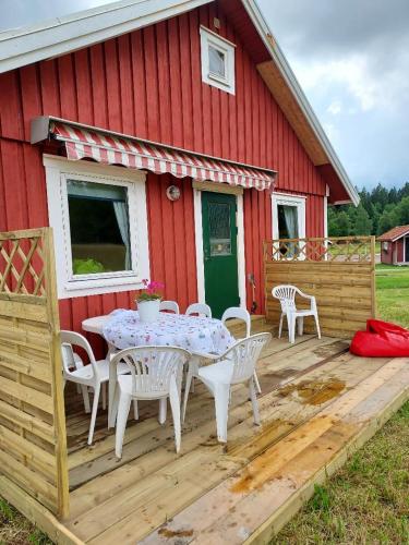 a wooden deck with a table and chairs in front of a red house at Älgbergets Bed & Breakfast in Ucklum