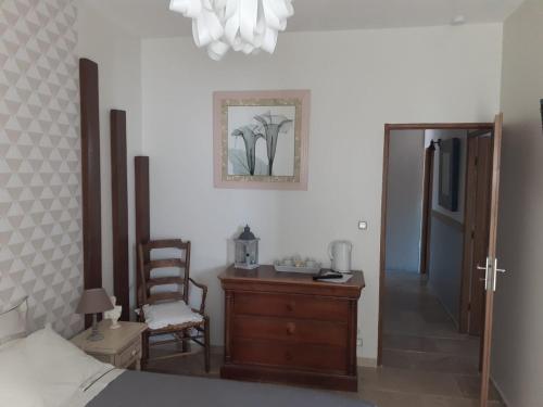 a bedroom with a bed and a chair and a dresser at les olivades in Magalas