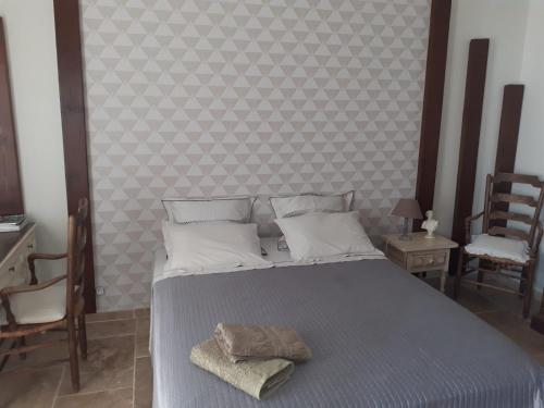 a bedroom with a bed with two chairs and a wall at les olivades in Magalas
