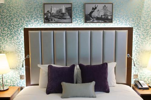 فندق ذا بلغريف في لندن: غرفة نوم بسرير مع صورتين على الحائط