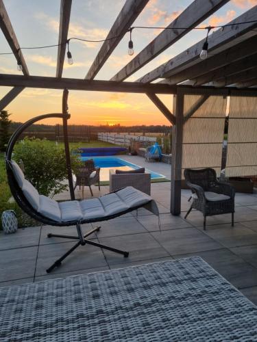 a patio with a swinging chair and a pool at Zagroda w Puszczy in Białowieża