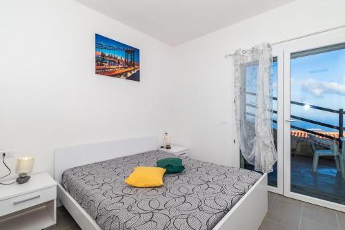 a bedroom with a bed with a yellow pillow and a window at Appartamento vista mare FT2 in Cascabraga