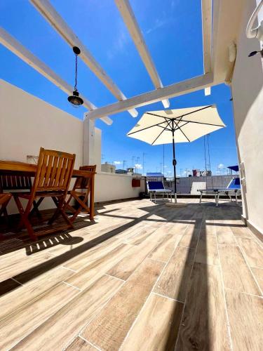 a patio with a table and an umbrella on a roof at Apulia Holidays in Mola di Bari