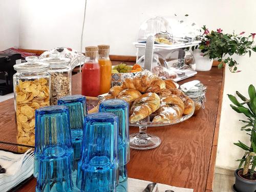 a table with a plate of pastries and blue glasses at Coastal B&B San Vito Lo Capo in San Vito lo Capo