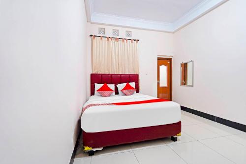 a bedroom with a bed with red and white sheets at OYO 91322 Jawara Guest House Syariah in Bandung