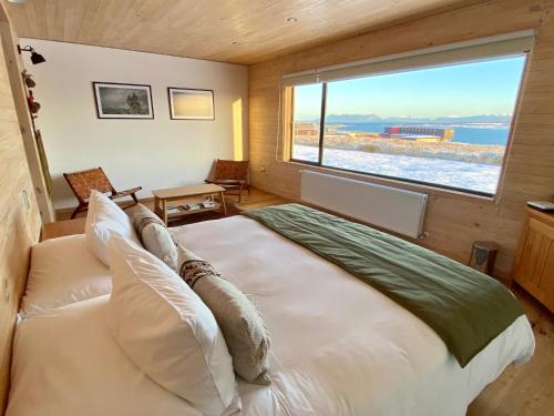 a bedroom with a large bed with a large window at Line Hotel Patagonia in Puerto Natales