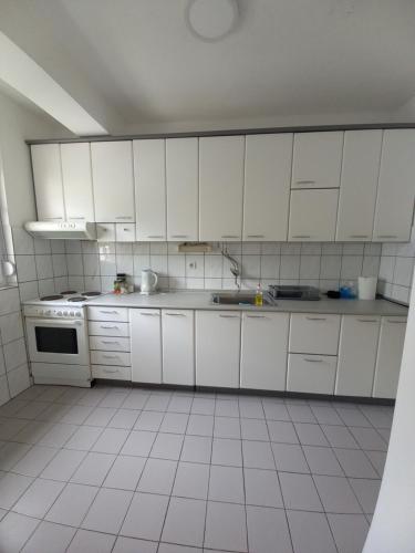 a kitchen with white cabinets and a white tiled floor at Katerina Apartment in Ohrid