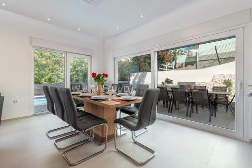a dining room with a wooden table and black chairs at Luxury Villa Sun Stone heated pool & whirlpool in Trogir