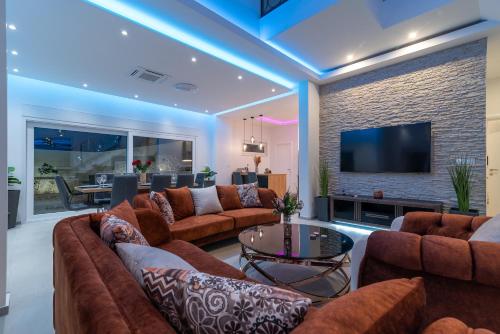 a living room with brown couches and a tv at Luxury Villa Sun Stone heated pool & whirlpool in Trogir