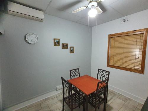 a dining room with a table and chairs and a clock on the wall at Casa de Romaria in Kimberley