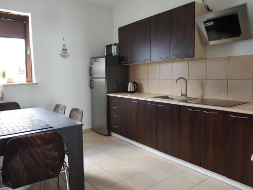 kuchnia z drewnianymi szafkami, stołem i lodówką w obiekcie Apt with 6 single beds w Świnoujściu