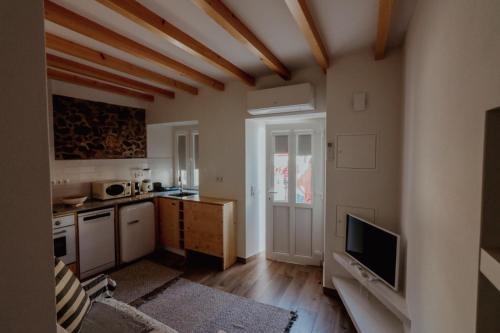 a kitchen with a living room with a tv and a kitchen at Refúgio do Paixão in Sesimbra