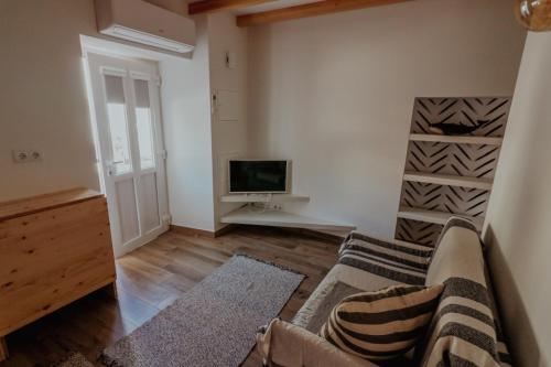 a living room with a couch and a tv at Refúgio do Paixão in Sesimbra