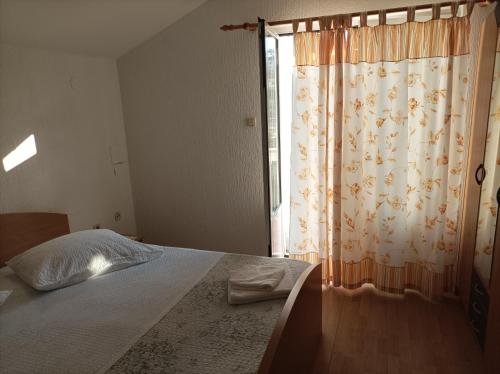 a bedroom with a bed with a curtain and a window at Feel Good Apartment Rab in Mundanije