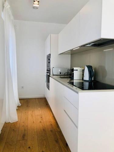 cocina con armarios blancos y suelo de madera en Adorable Apartment City Center with Parking, Near Tram, en Luxemburgo