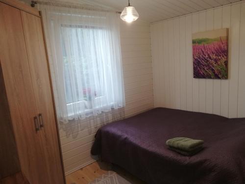 a small bedroom with a bed and a window at Poilsio namelis po juodalksniais (Nemirseta) in Palanga