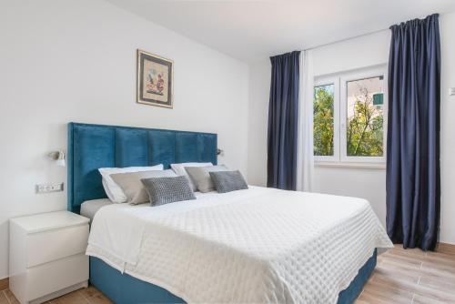 Schlafzimmer mit einem großen Bett mit blauem Kopfteil in der Unterkunft Apartment Kiki in Kaštel Štafilić