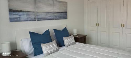 a bedroom with a white bed with blue pillows at Precioso apartamento con piscina junto al mar in Costa Del Silencio