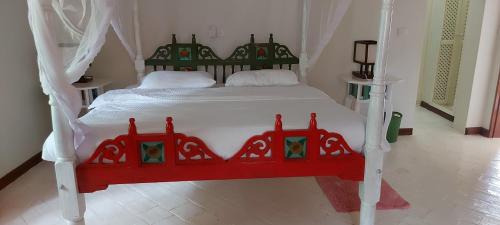a bedroom with a red and white bed in a room at The Villa Mela, Malindi in Malindi