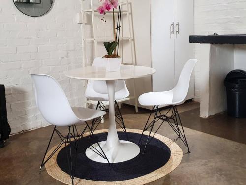 uma mesa branca e quatro cadeiras num quarto em Craftsmen's ship Maboneng, Apartment em Joanesburgo
