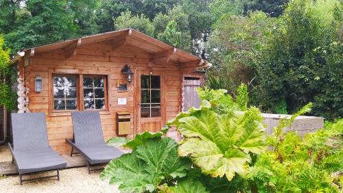 eine kleine Holzhütte mit zwei Stühlen davor in der Unterkunft Manoir Desnachez in Taupont