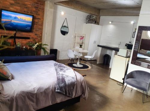 um quarto com uma cama, uma mesa e uma televisão em Craftsmen's ship Maboneng, Apartment em Joanesburgo