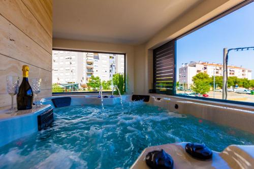 a hot tub with a bottle of wine and a window at Mrak Zadar Exclusive in Zadar