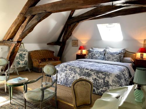 ein Schlafzimmer mit einem Bett und Stühlen im Dachgeschoss in der Unterkunft Manoir de La Croix Saint Louis "Luxury Guest House" in Taingy
