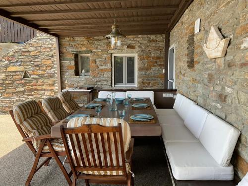 a dining room with a table and chairs and a stone wall at KeaSouth in Koundouros