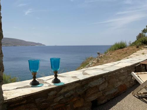 two blue glasses sitting on a stone wall near the water at KeaSouth in Koundouros