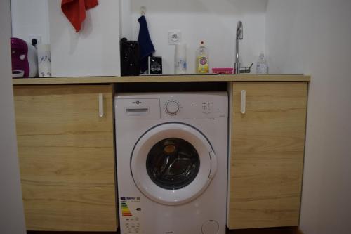 a washing machine in a kitchen under a counter at Appartement La JOIE dans quartier chic in Pibrac