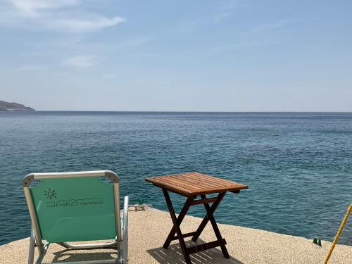 a table and a chair sitting next to the water at KeaSouth in Koundouros