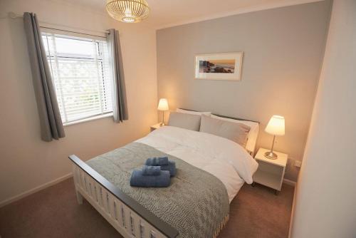 a bedroom with a large bed with a blue seat at 3-Bedroom bungalow with parking, Goldsithney, Penzance, Cornwall in Perranuthnoe