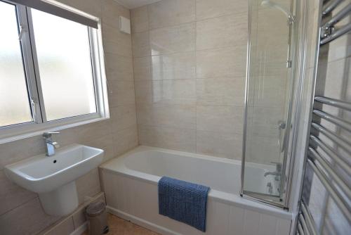 a bathroom with a tub and a sink and a shower at 3-Bedroom bungalow with parking, Goldsithney, Penzance, Cornwall in Perranuthnoe