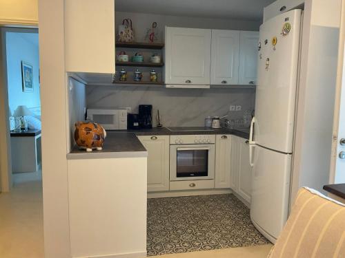 a kitchen with white cabinets and a white refrigerator at KeaSouth in Koundouros