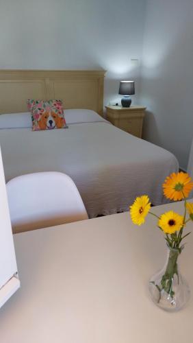 1 dormitorio con 1 cama con flores amarillas en un jarrón en Casita El Parral II, en Puntagorda