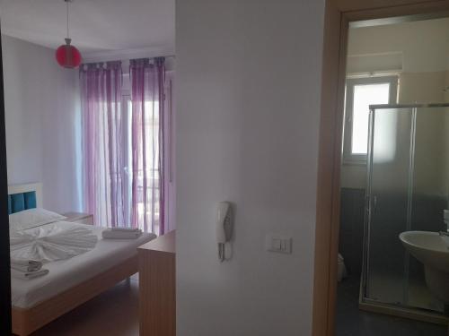 1 dormitorio con cama, lavabo y ducha en The Blue Horizon, en Vlorë