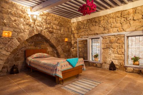 a bedroom with a bed in a stone wall at Nzar Khoury for Hosting in Acre
